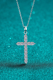 Moissanite cross pendant necklace displayed on teal background