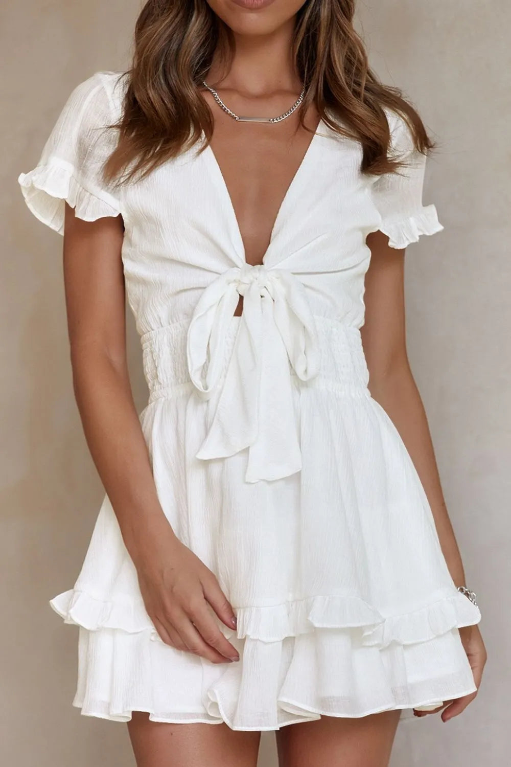 Front view of white tie-front mini dress with flutter sleeves and ruffled skirt