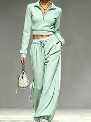 Model wearing mint green half-zip crop top and matching wide-leg pants