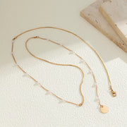 Gold-tone pearl station necklace with round coin pendant arranged flat