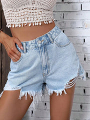 Close-up of front pocket and distressed hem on denim shorts