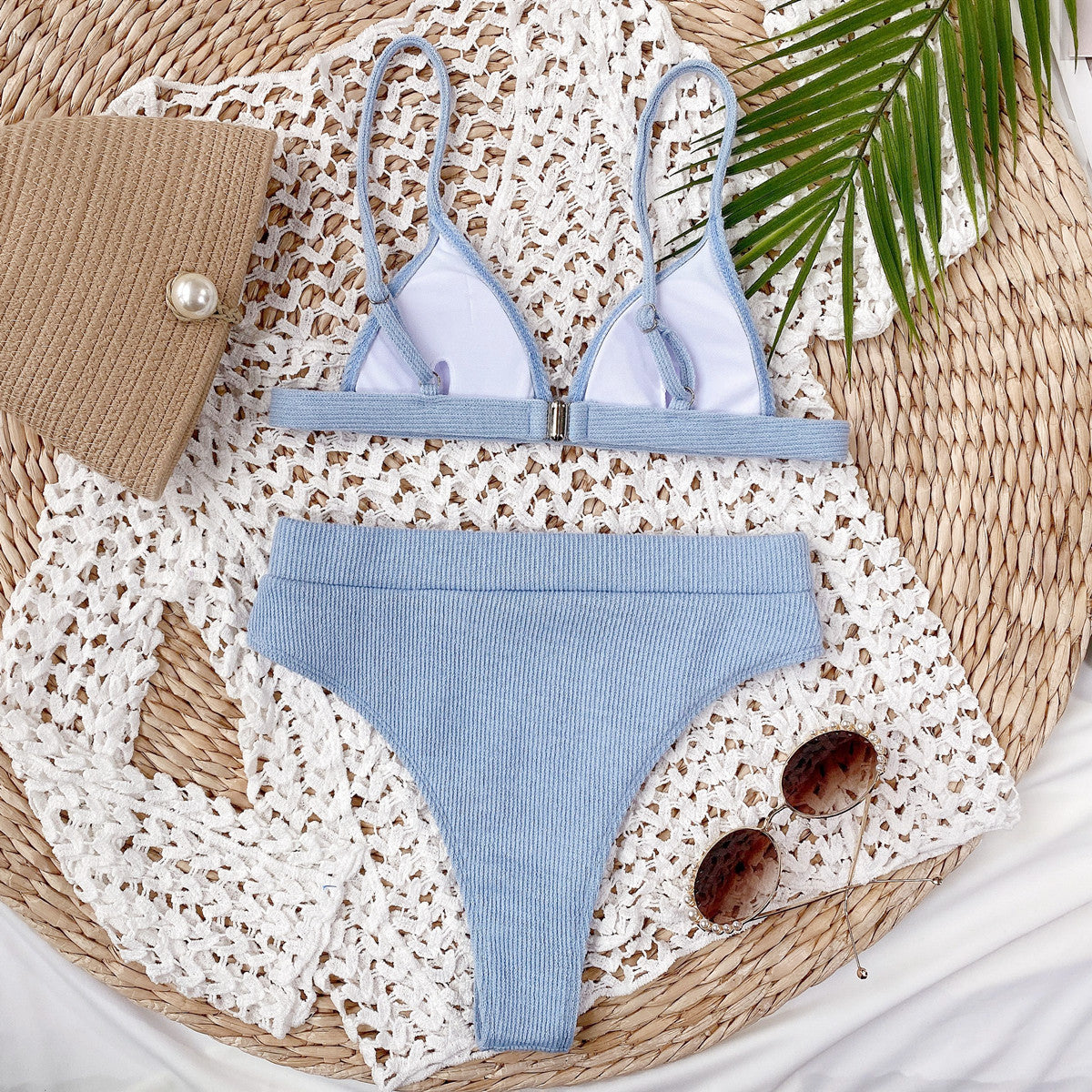 Light blue ribbed bikini set laid flat in a woven basket with sunglasses