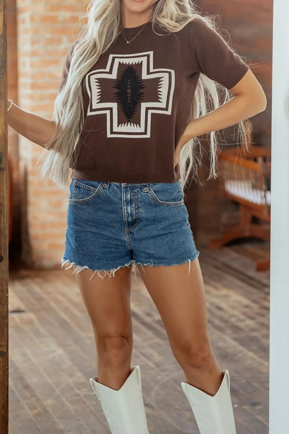Full-length view of brown western graphic tee styled with denim shorts and white boots