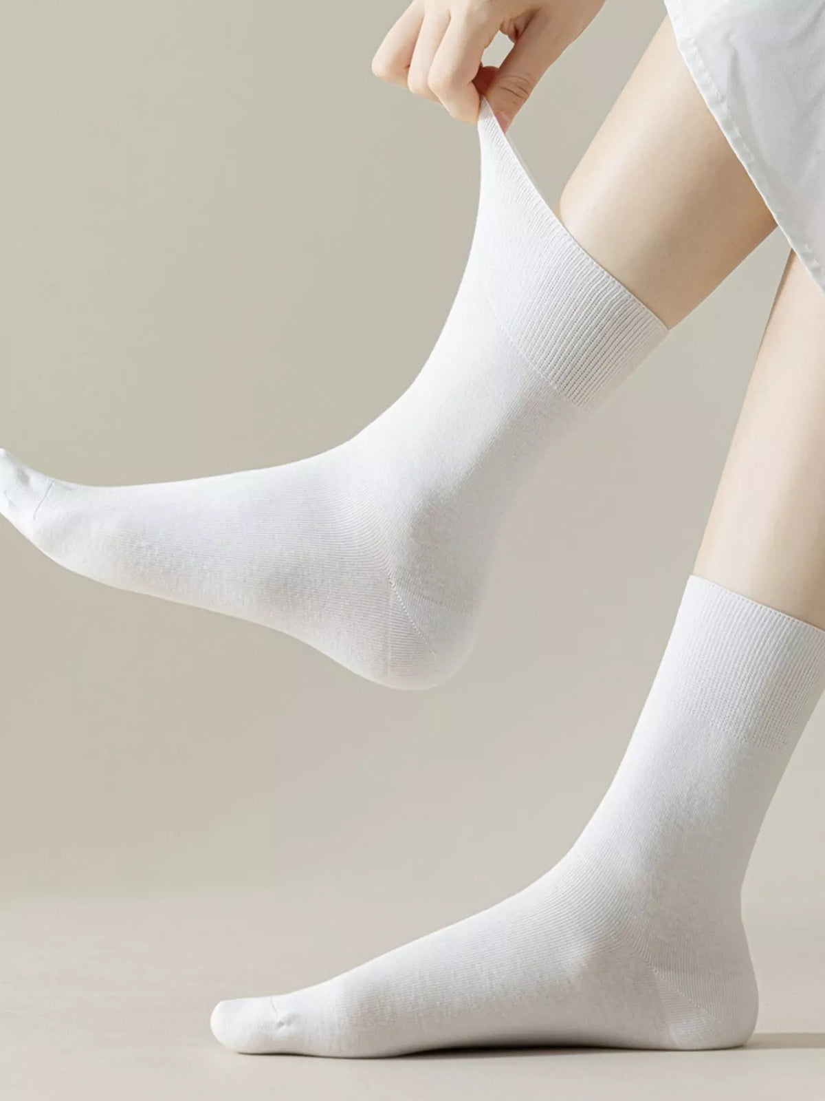 Close-up of a white mid-calf sock being stretched to show its shape