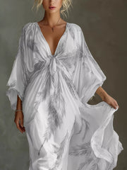Close view of the grey feather-print maxi dress showing its tied V-neckline and gathered front.