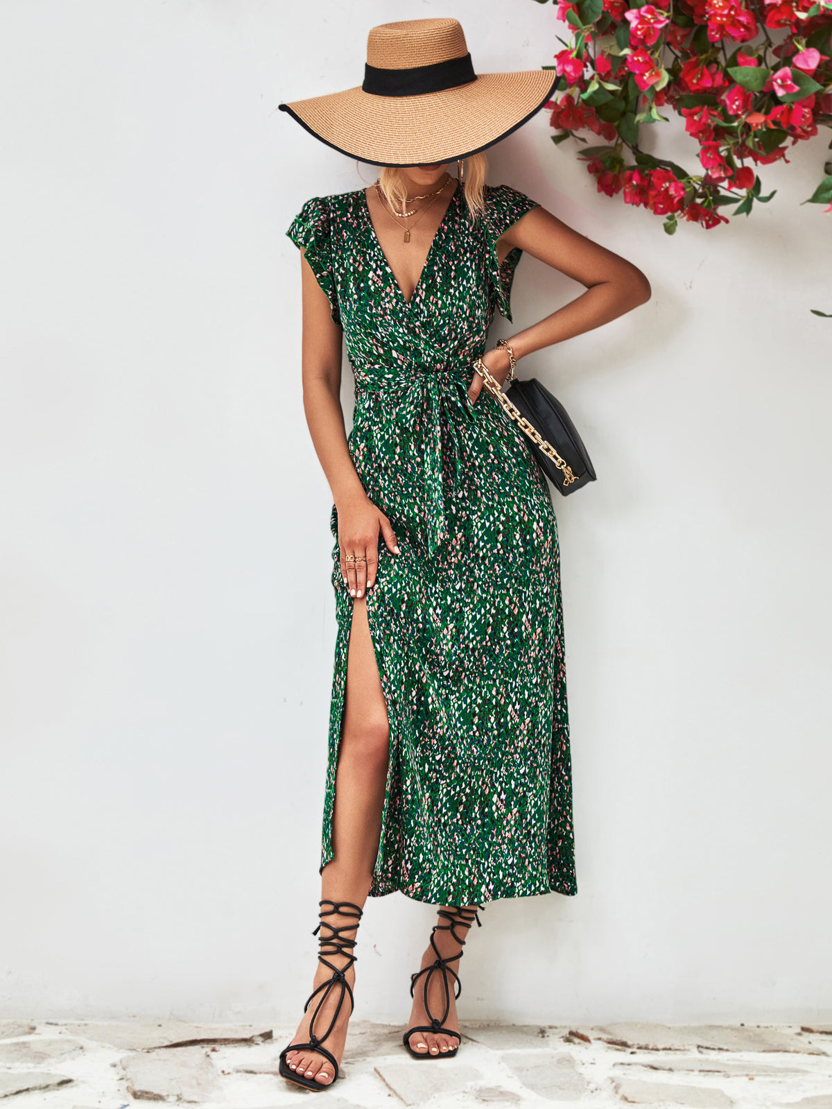 Green printed V-neck dress with a side slit, shown on a model carrying a shoulder bag.