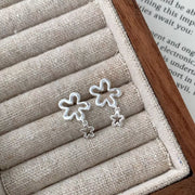 Pair of flower drop earrings displayed on a fabric jewelry tray