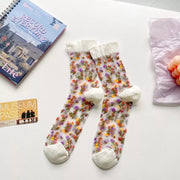 Pair of light sheer crew socks with colorful floral pattern and white cuffs and toes