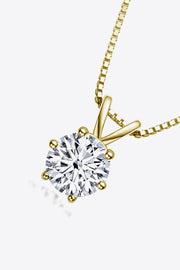 Angled close-up of a gold-tone solitaire pendant and clear round stone