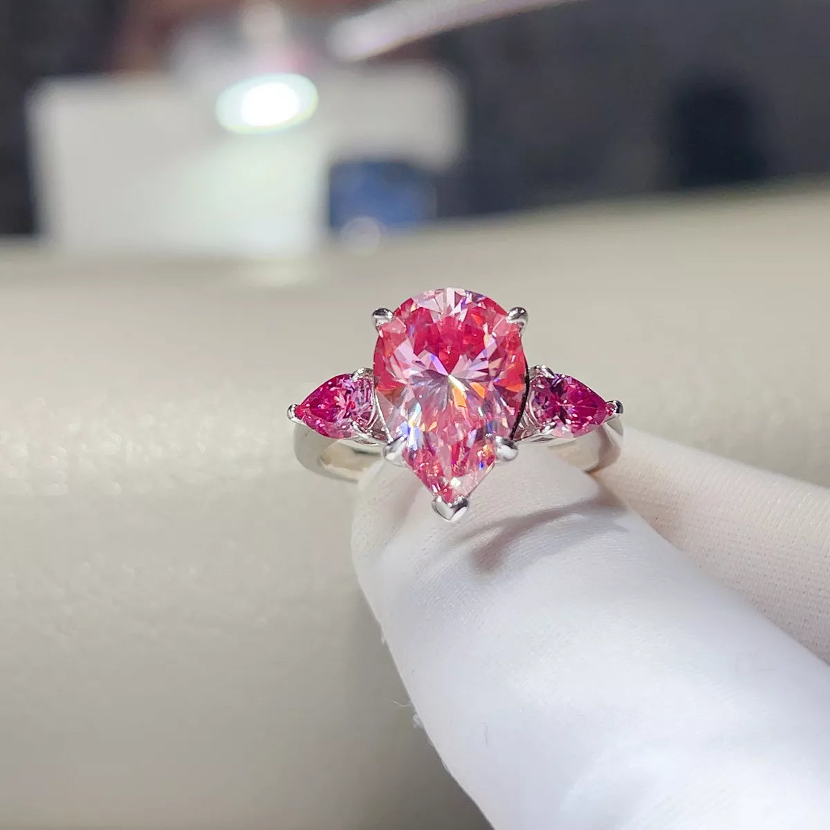 Close front view of the pink teardrop moissanite ring on a display glove