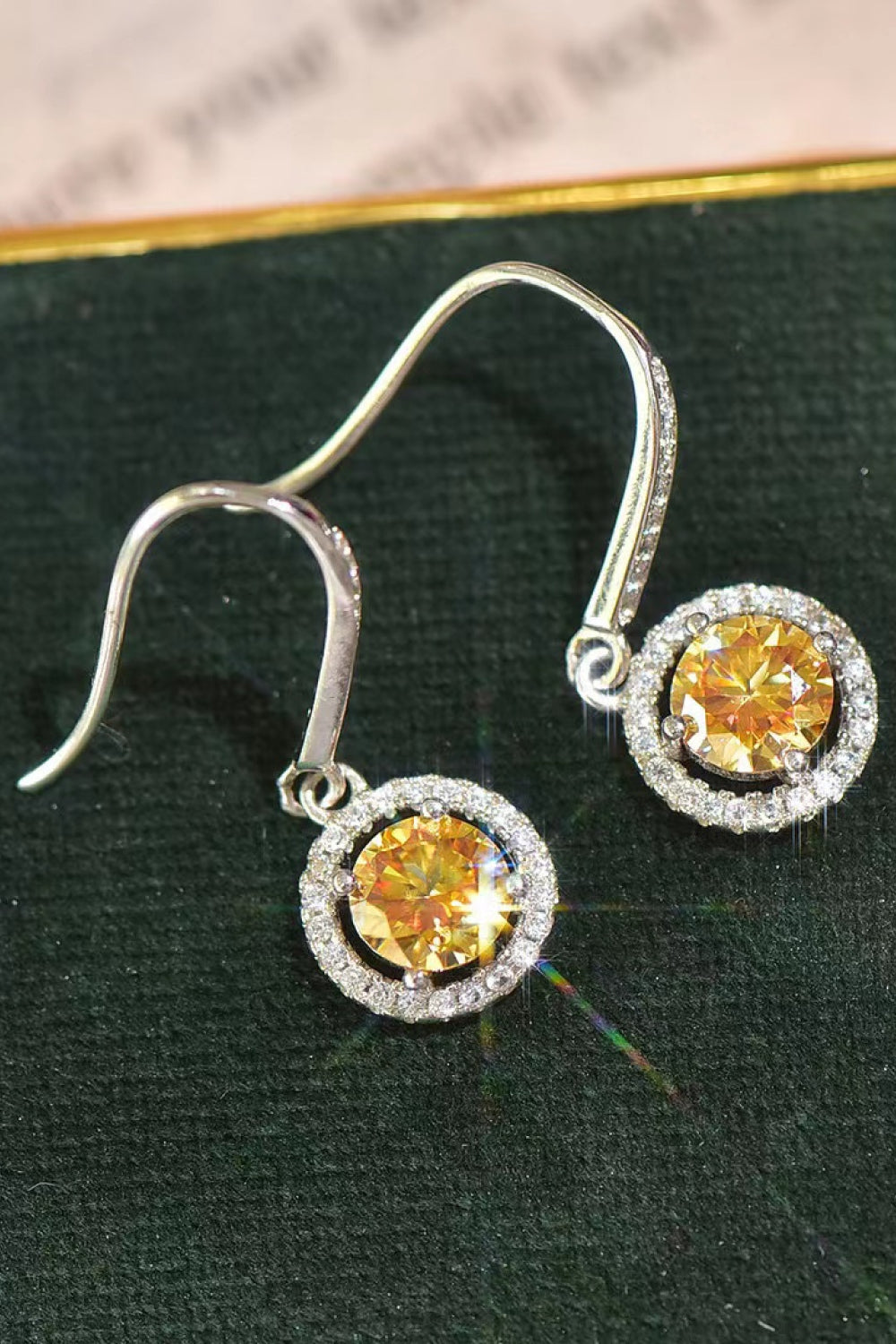 Platinum-Plated 2 Carat Moissanite Drop Earrings — Close-up of yellow moissanite drop earrings on dark fabric