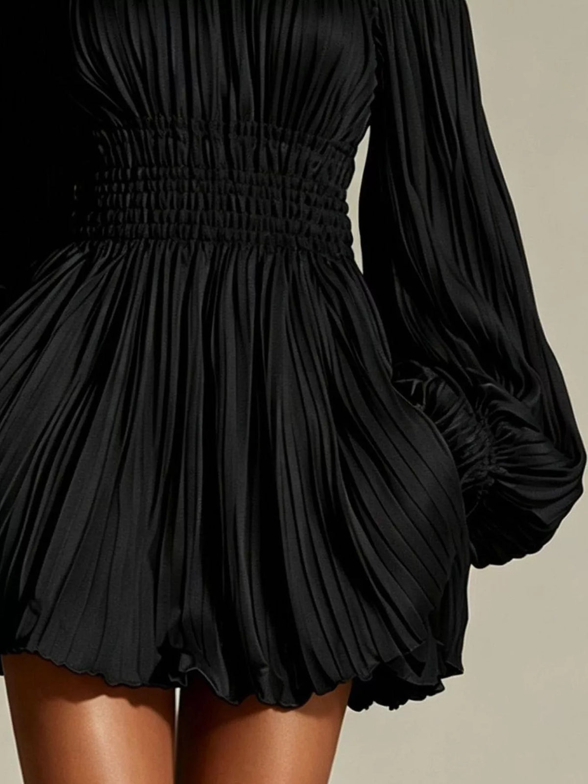 Close view of black dress's pleated bodice and smocked waist
