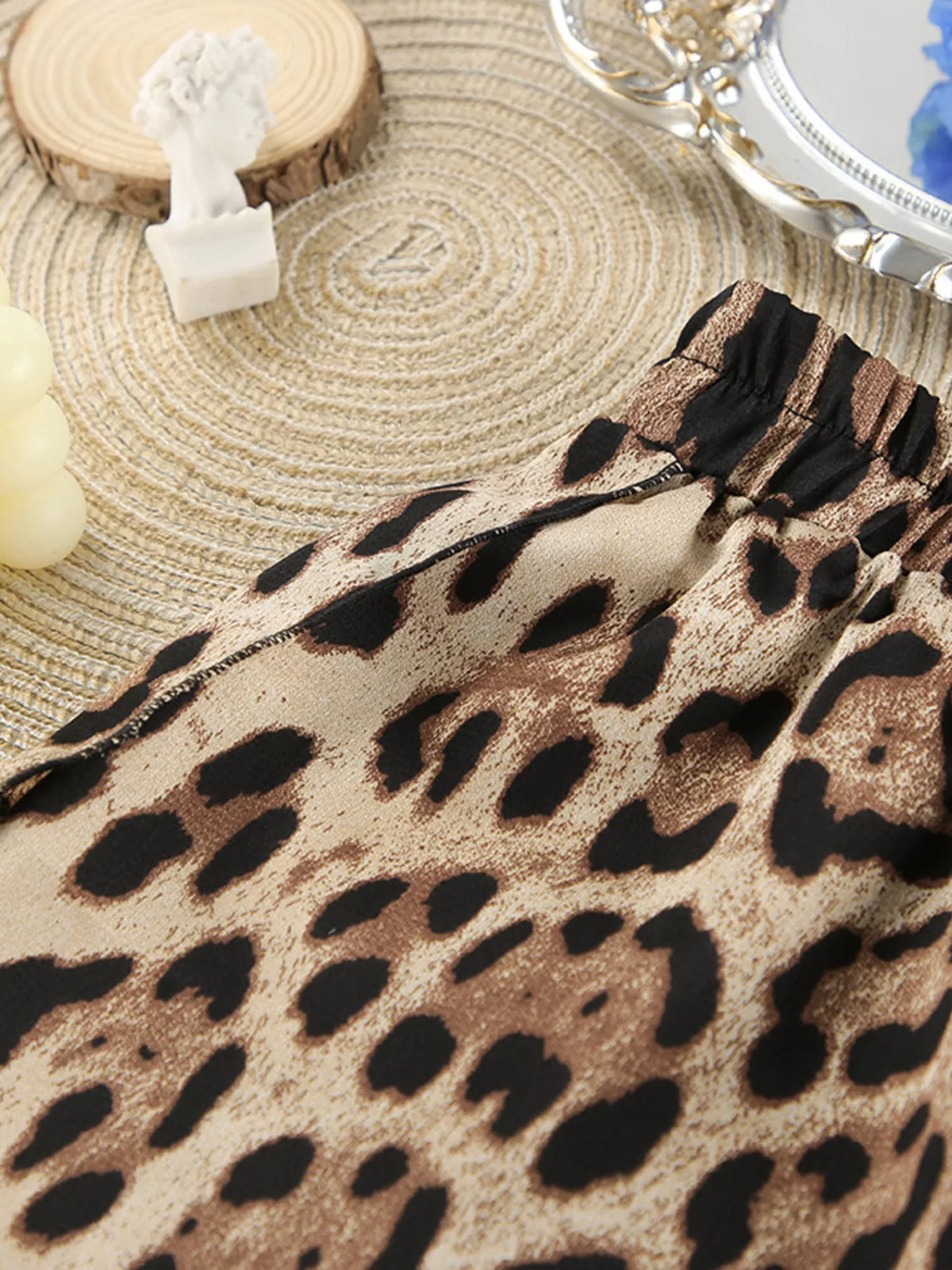 Close view of leopard-print garment fabric arranged on a woven mat