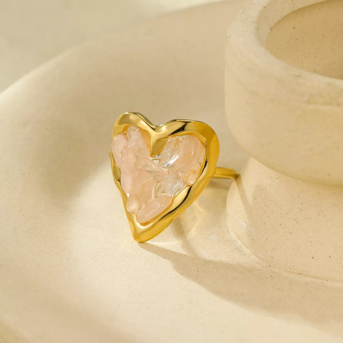 Gold-plated heart-shaped ring with pale pink stones shown at an angle