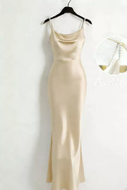 Cream satin cowl-neck maxi dress with pearl straps on a hanger.