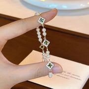 Geometric bracelet held up to show square accents and pearl beads