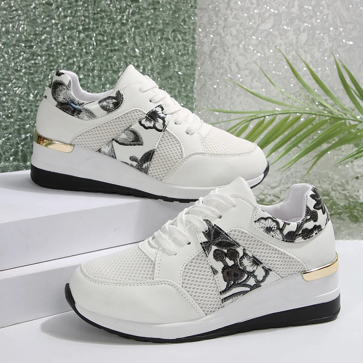 Pair of white sneakers with black floral panels and white soles, side view