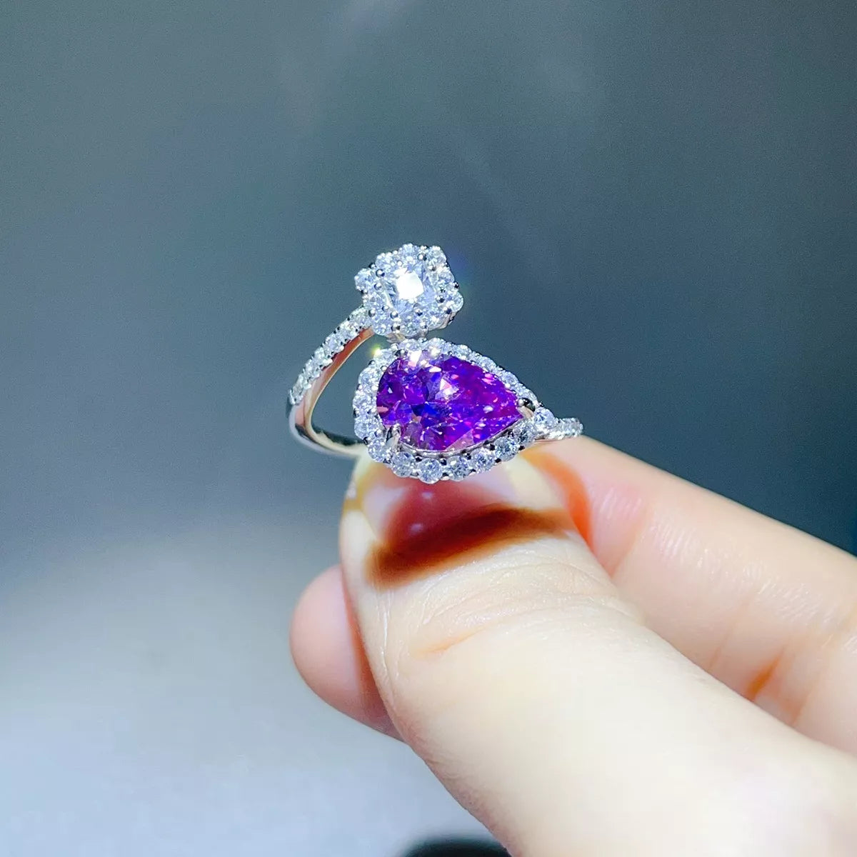 Side angle of the purple teardrop moissanite ring showing its curved silver band