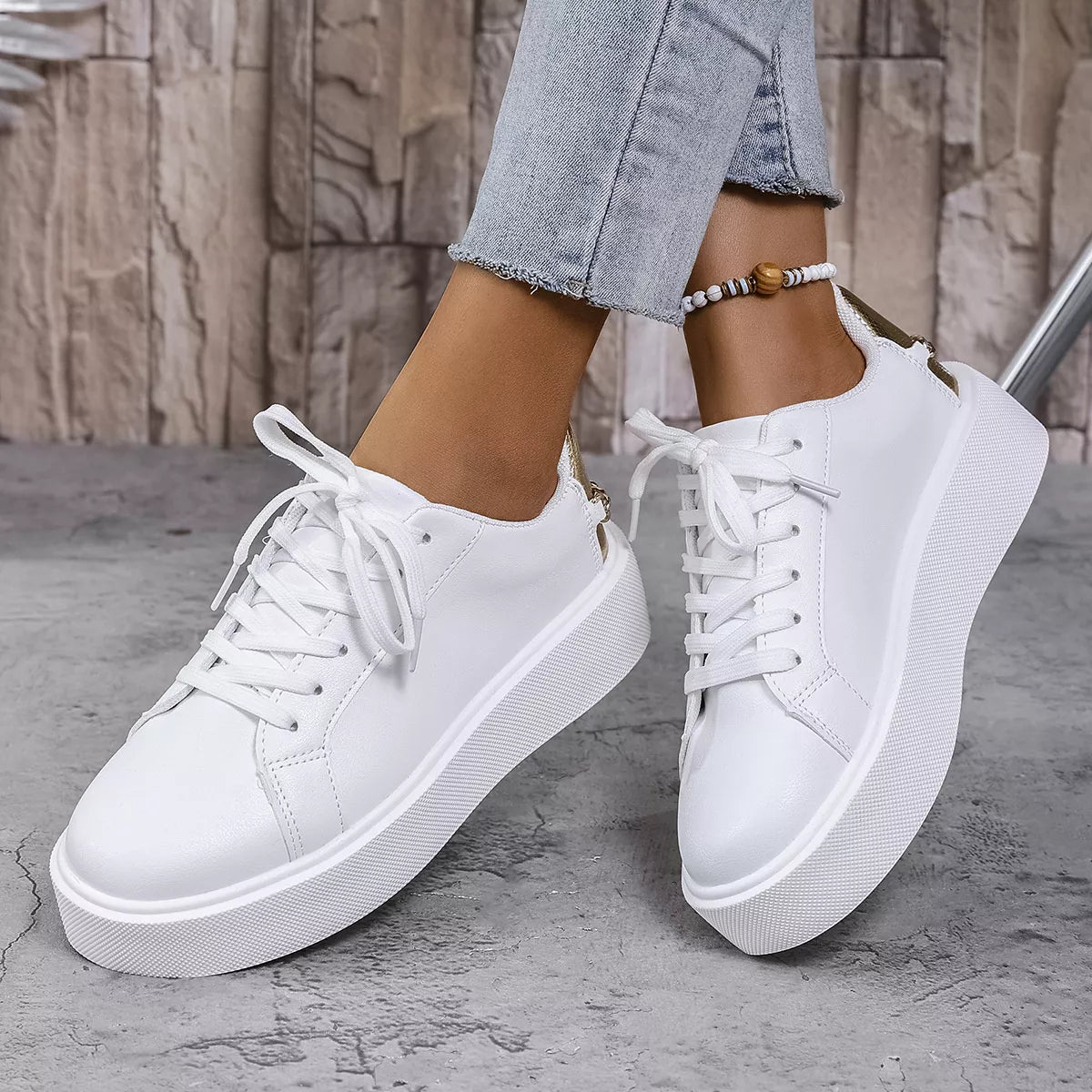 Pair of white lace-up platform sneakers worn with cropped jeans