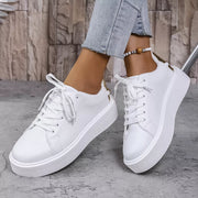 Pair of white lace-up platform sneakers worn with cropped jeans