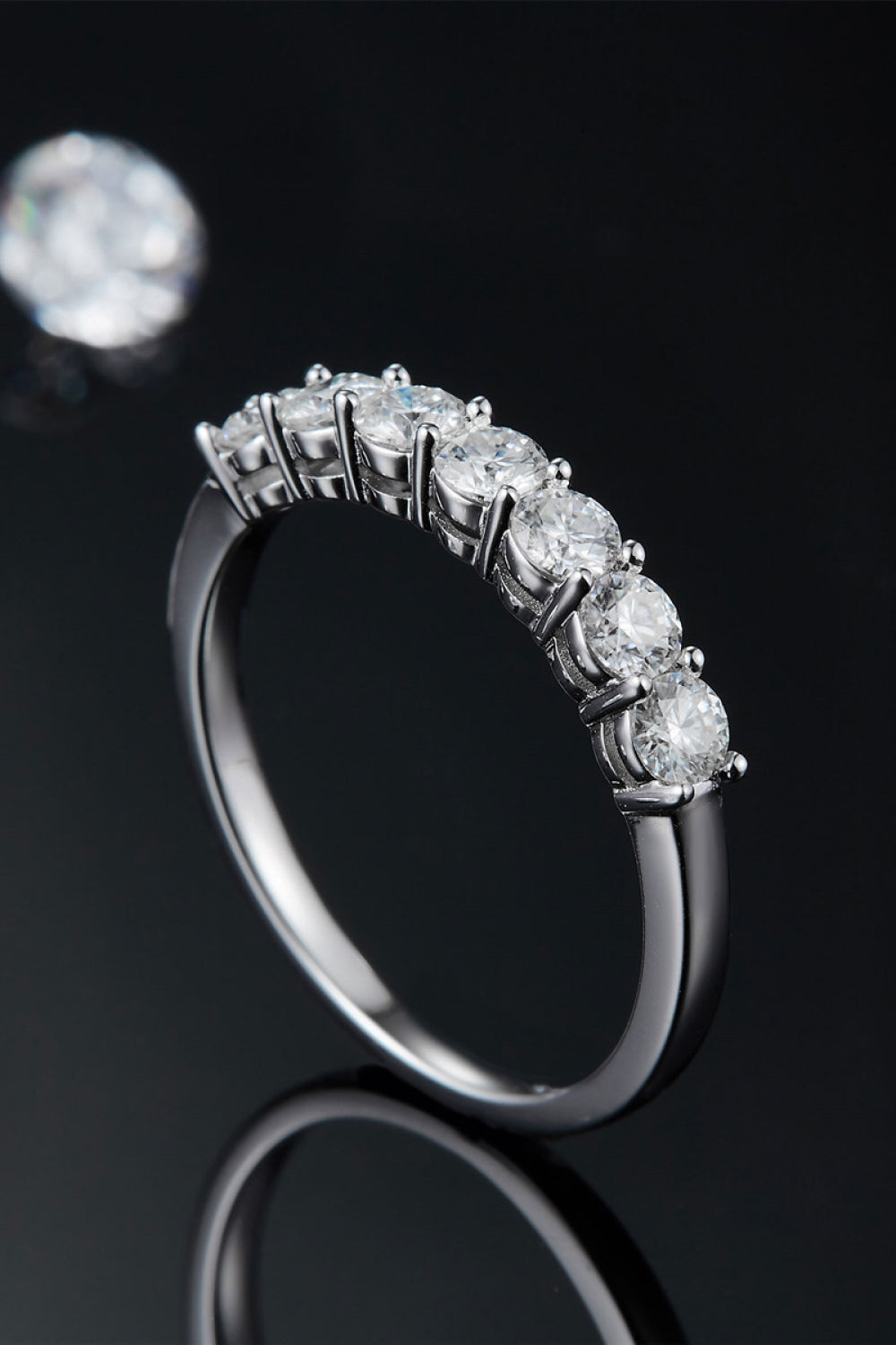 Side view of silver-tone ring showing raised round stones and settings against black