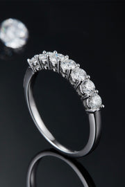 Side view of silver-tone ring showing raised round stones and settings against black