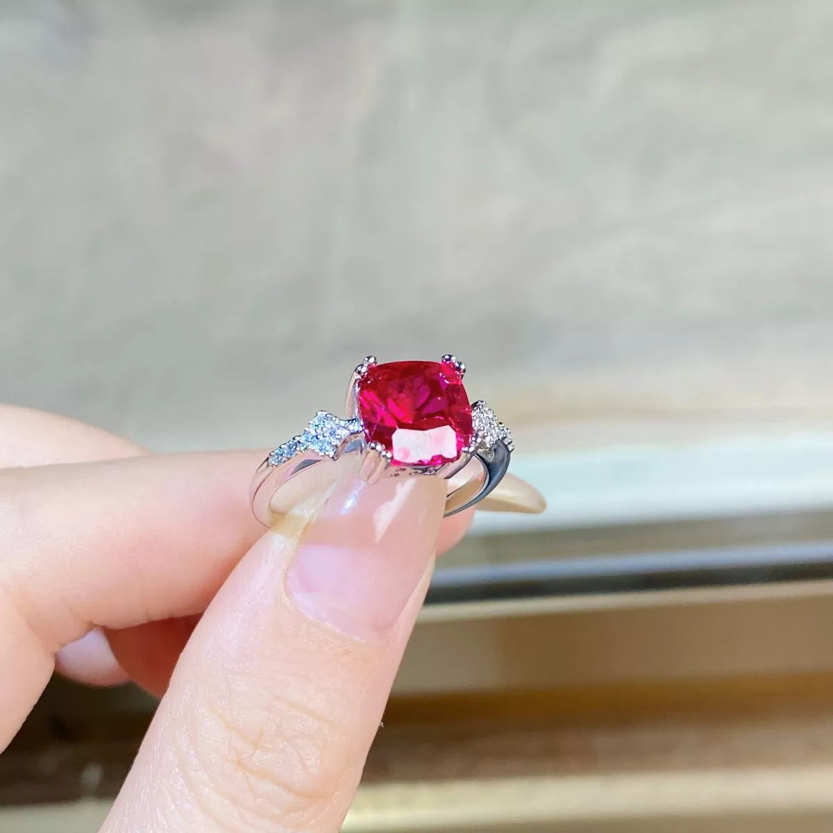 Red rectangular zircon ring shown on a hand.