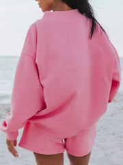 Back view of a bright pink oversized sweatshirt and matching shorts.