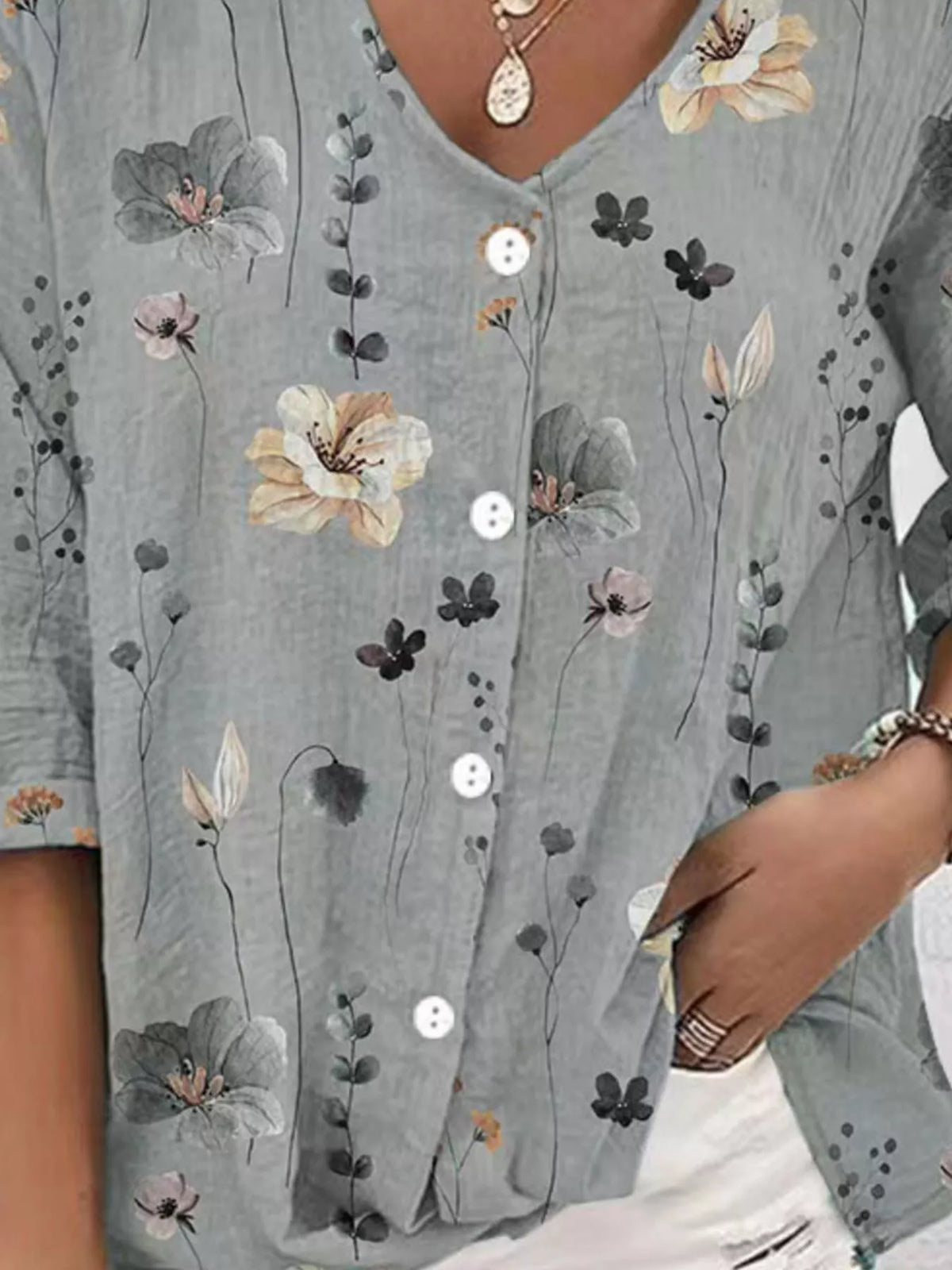 Close view of gray blouse with white and blue flowers and buttons.