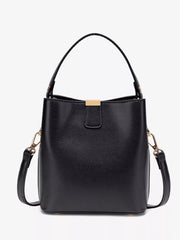 Straight-on view of the black bucket bag with the short handle, detachable strap, and gold-tone clasp.