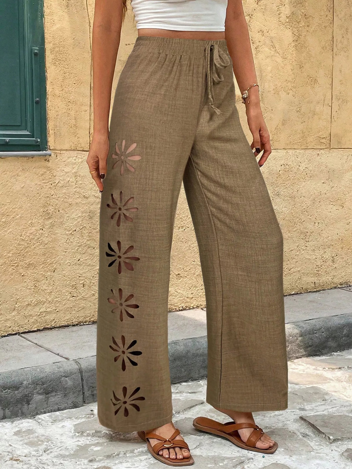 Model wearing taupe wide-leg pants with floral cutout pattern