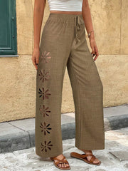 Model wearing taupe wide-leg pants with floral cutout pattern