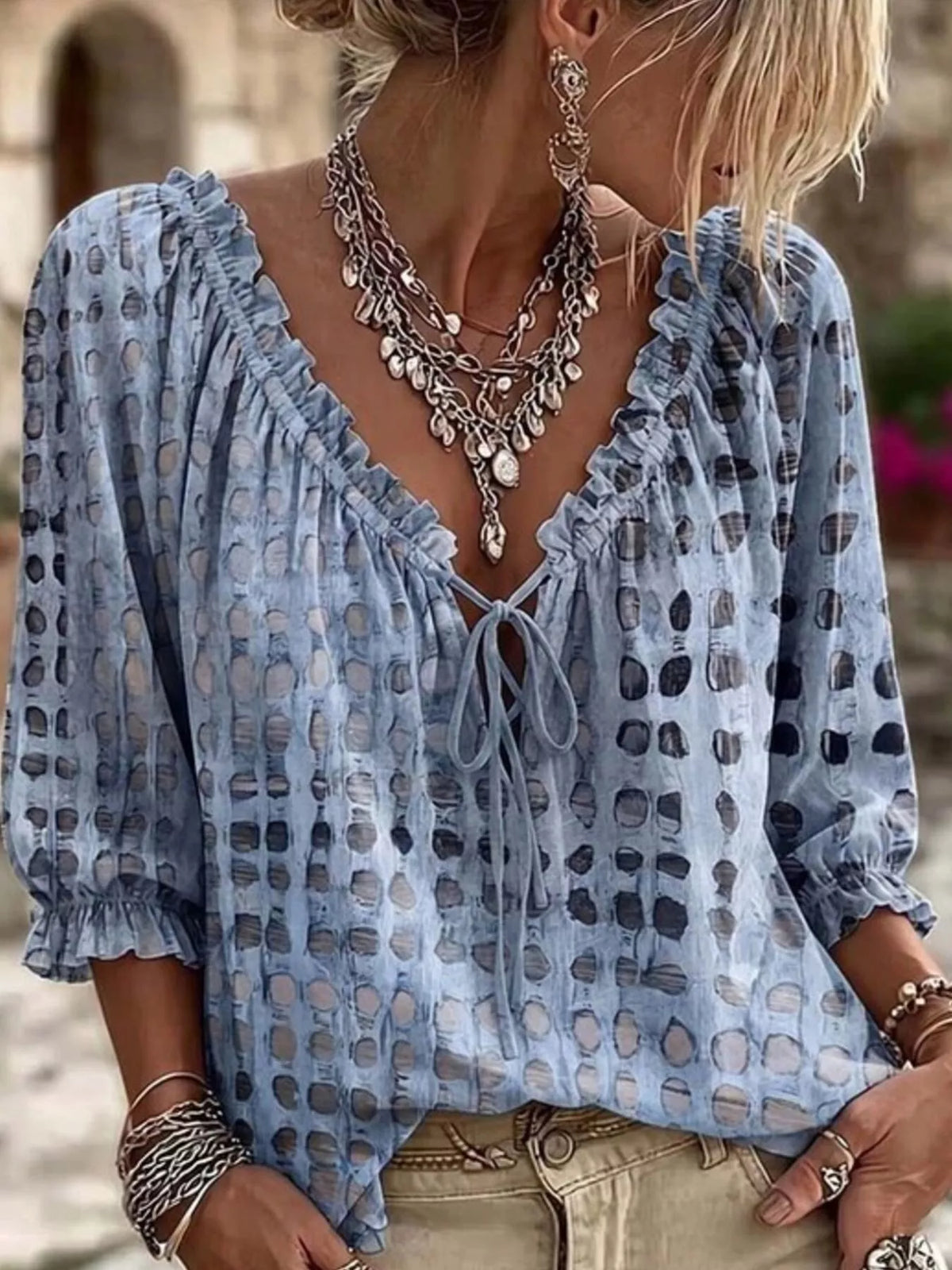 Light blue geometric-print tie-neck blouse worn with beige jeans.