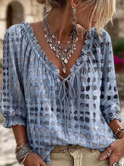 Light blue geometric-print tie-neck blouse worn with beige jeans.