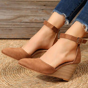 Tan pointed-toe wedge sandals shown from the side on feet