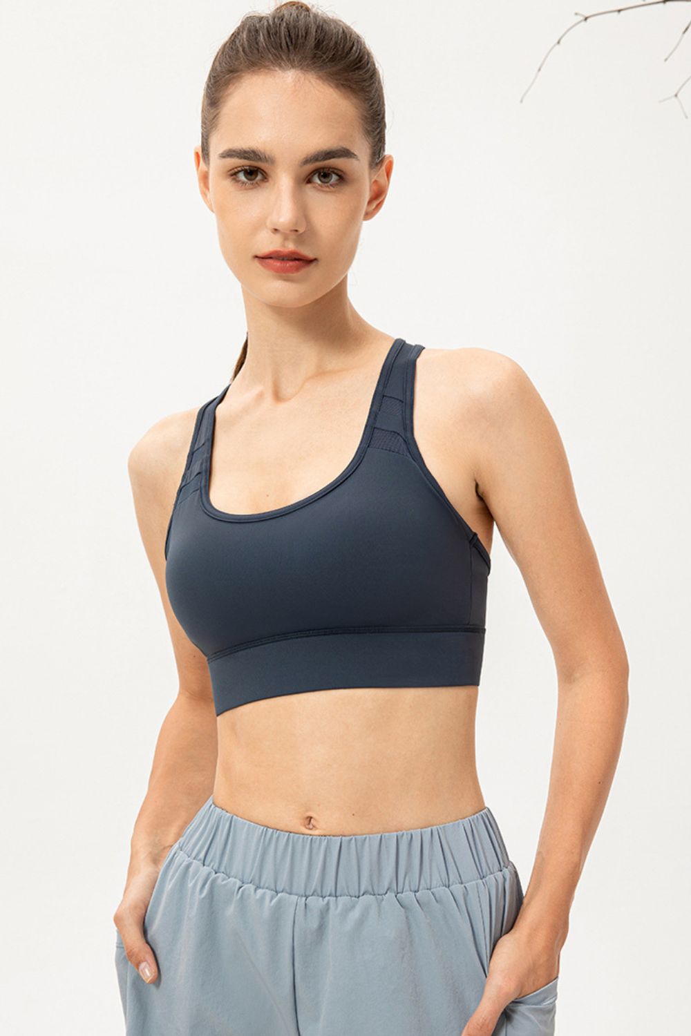 Model wearing navy scoop-neck sports bra, front view