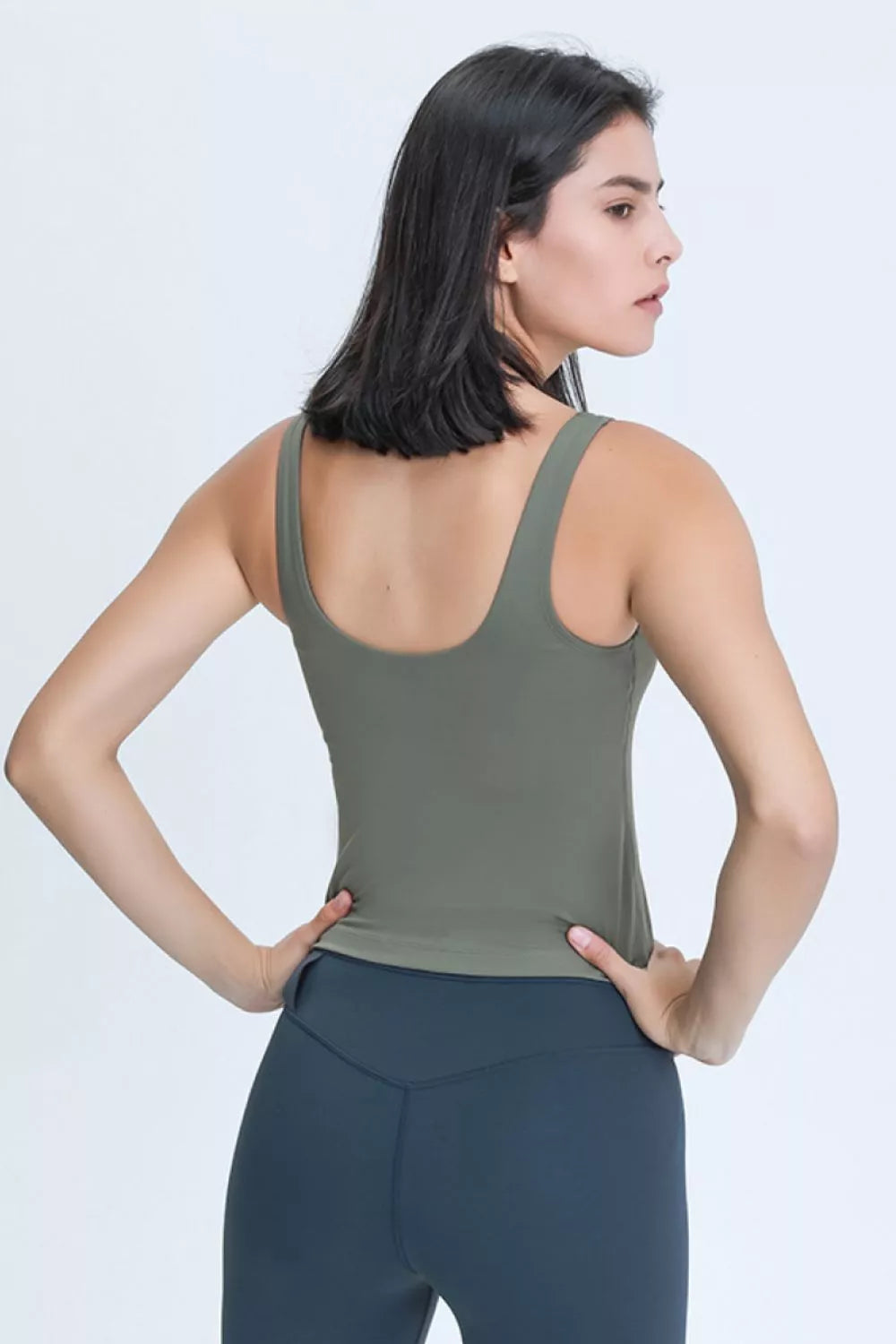 Front view of a woman wearing an olive green V-neck active tank.