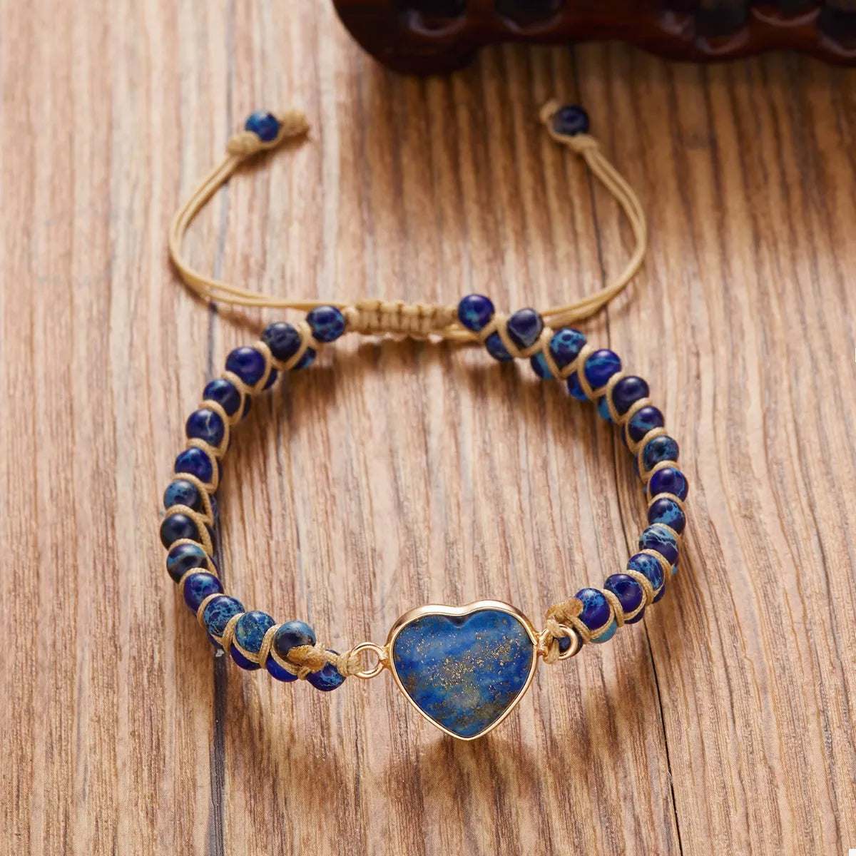 Navy beaded heart bracelet laid flat on wood with the adjustable cords extended.
