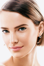 Gold-tone crisscross hoop earrings worn by a model