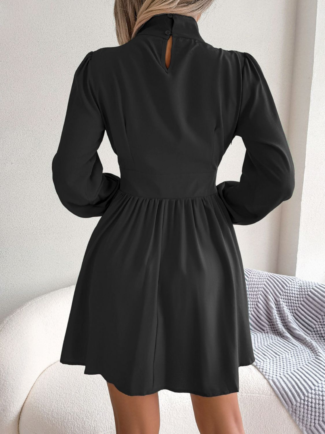 Back view of black cutout turtleneck A-line mini dress