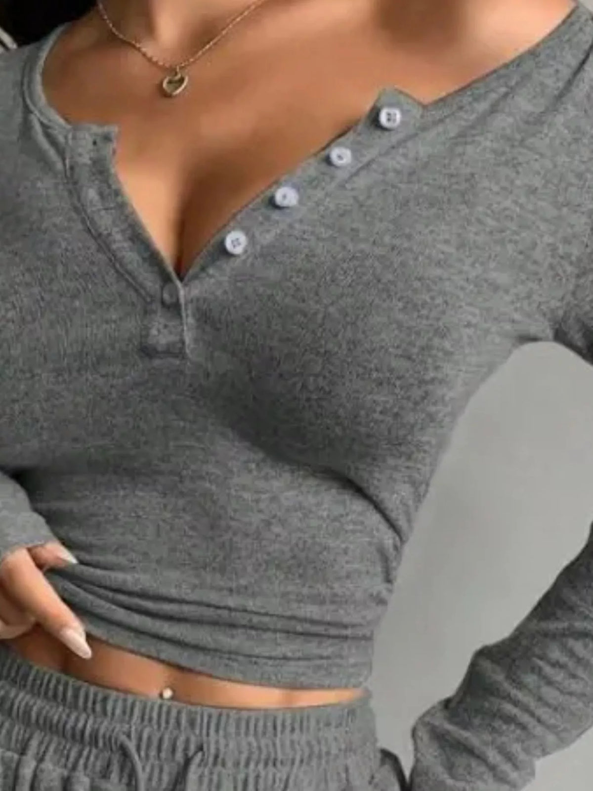 Close-up of dark grey top showing the diagonal button neckline and long sleeve