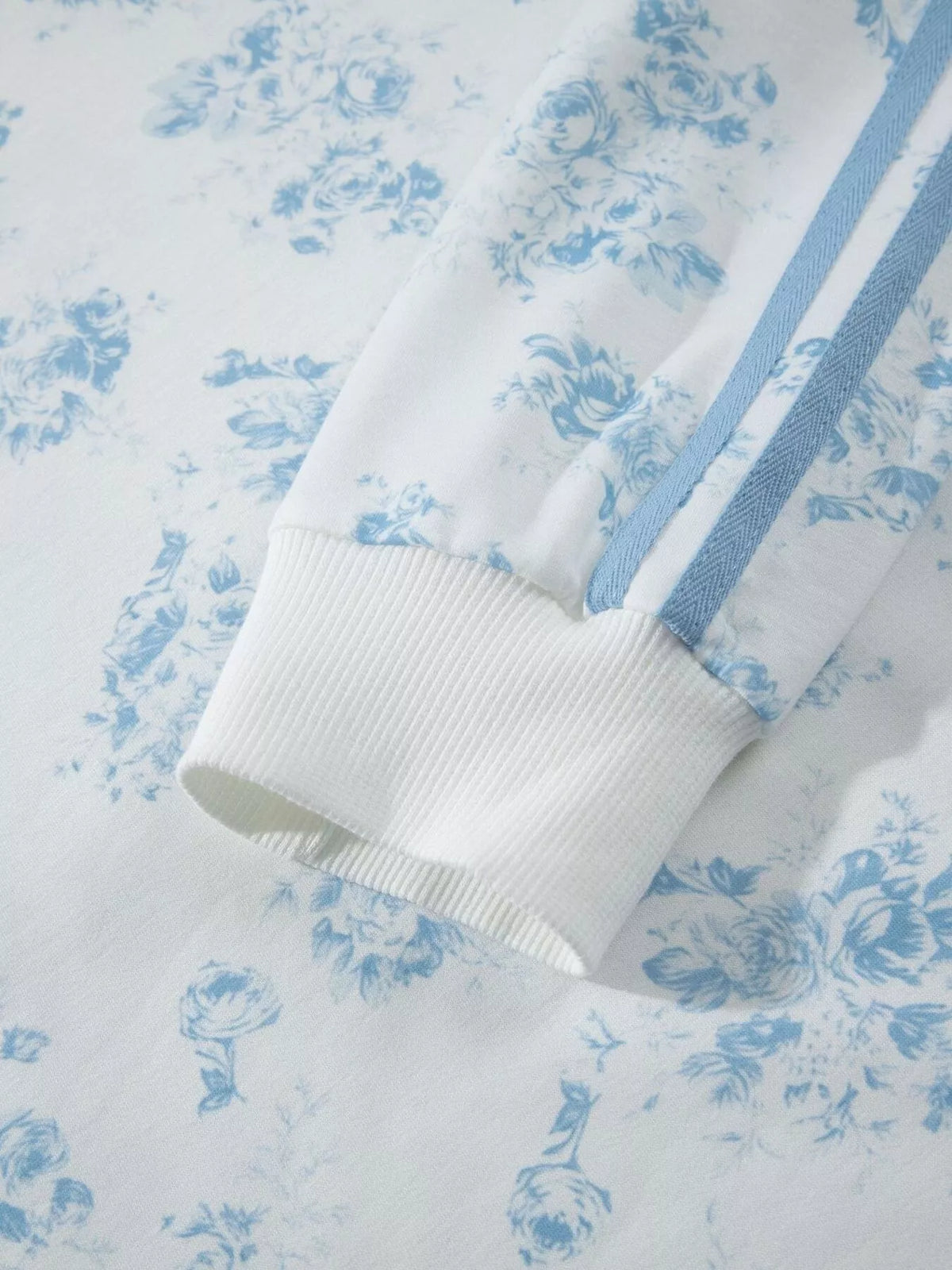 Close-up of ribbed cuff and blue stripe on floral sweatshirt sleeve