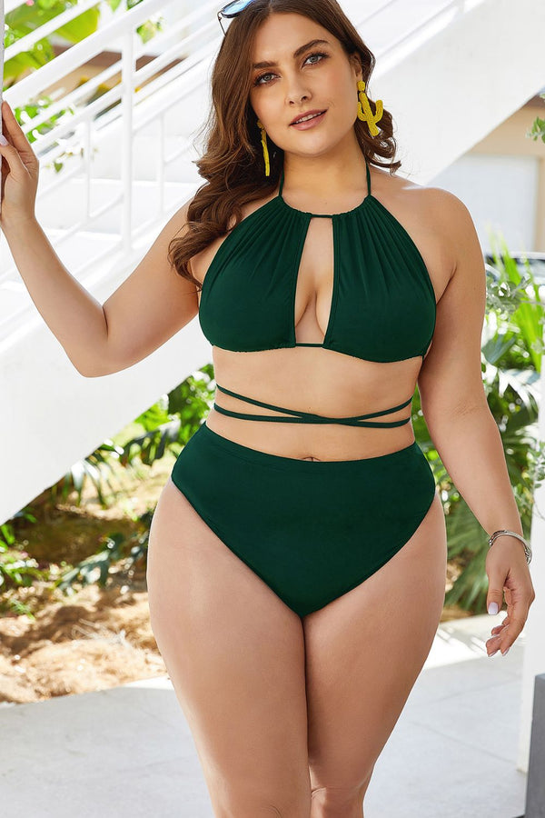 Dark green halter bikini with a front cutout and high-waisted bottoms, worn beside outdoor steps