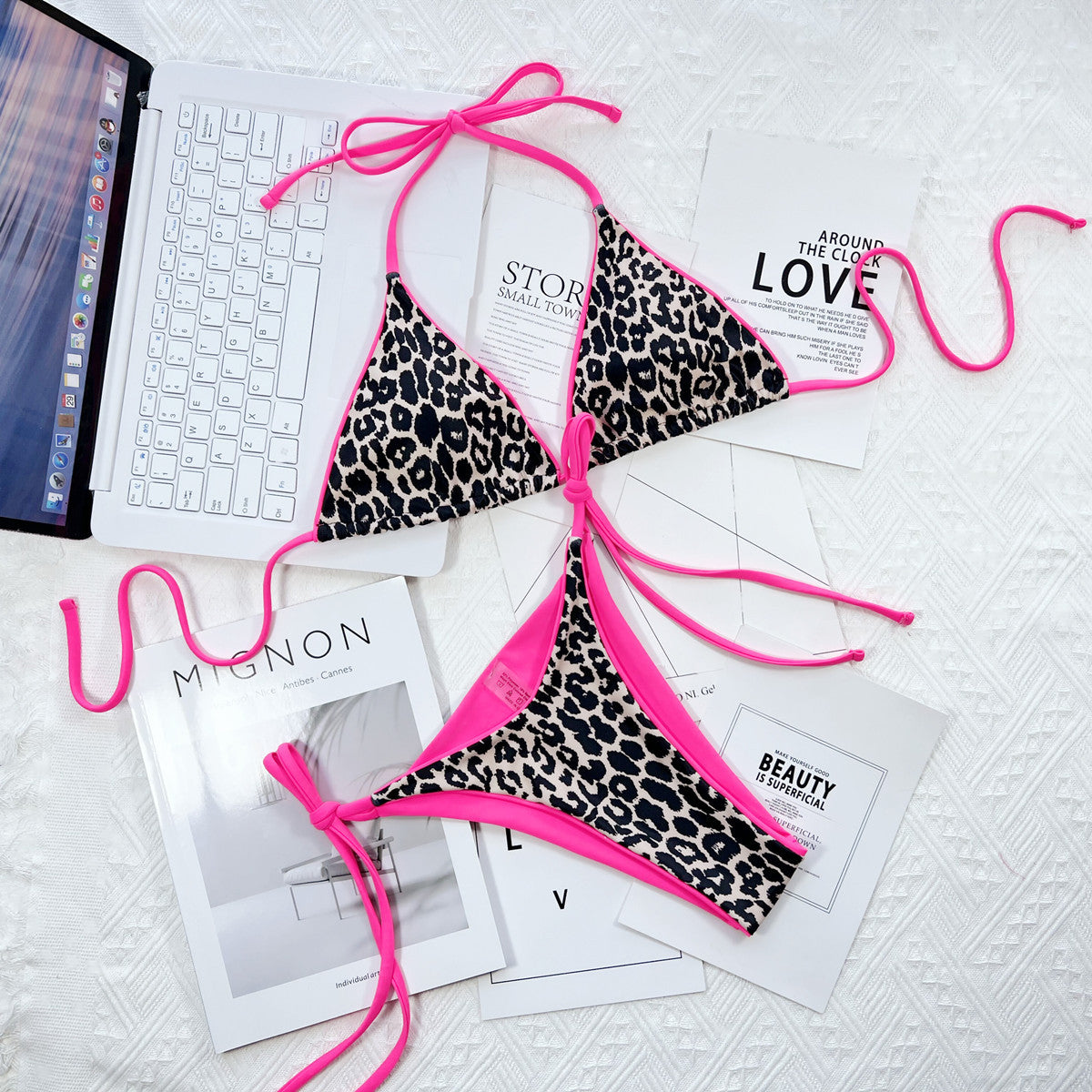 Pink-trimmed leopard bikini set laid flat beside keyboard