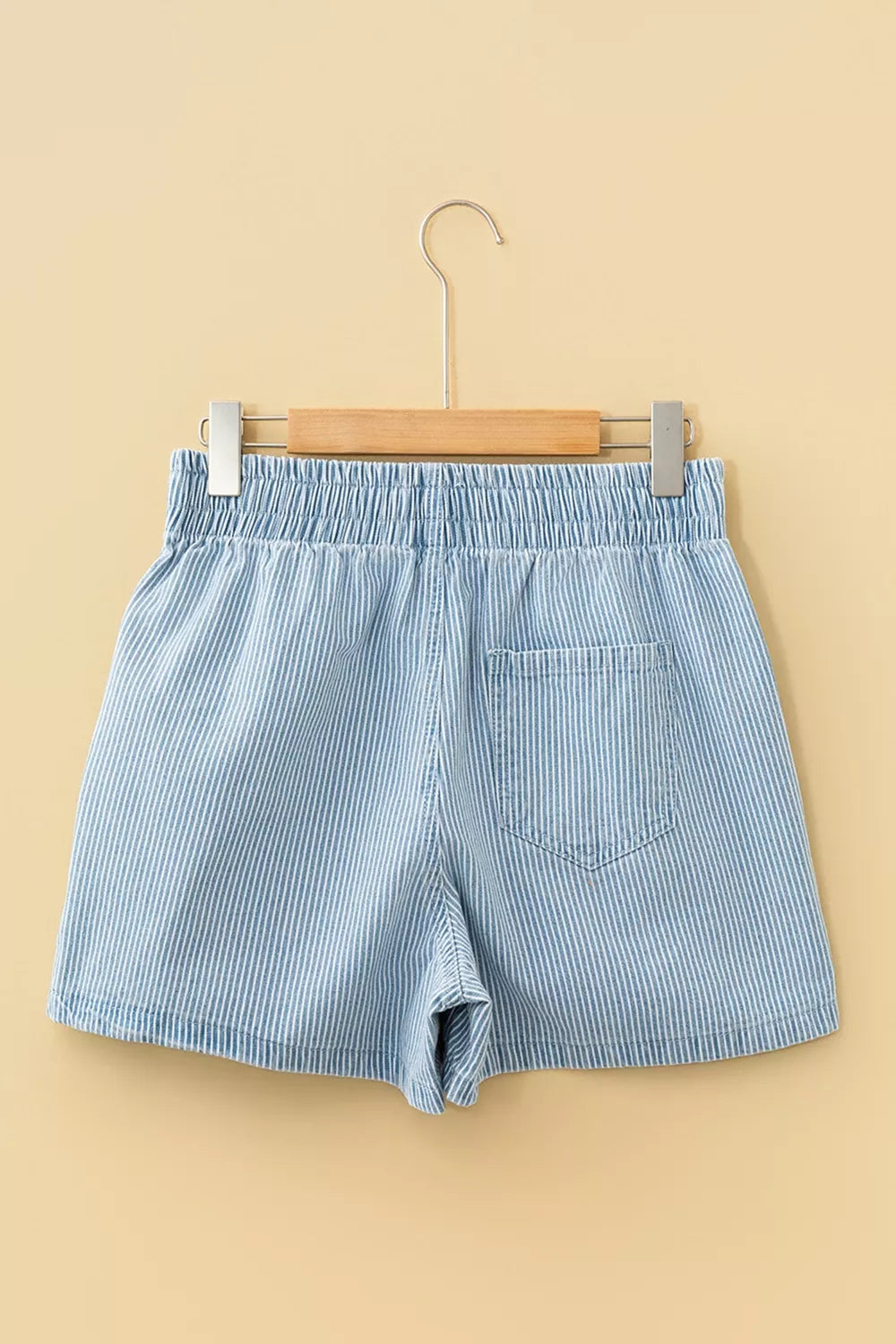 Back product view of light blue striped shorts on a wooden hanger.