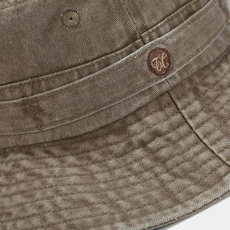 Close-up of the stitched band and small emblem on the khaki bucket hat