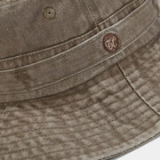 Close-up of the stitched band and small emblem on the khaki bucket hat