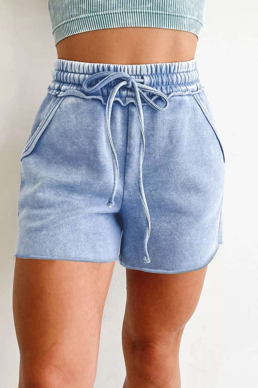 Front view of light-blue drawstring shorts worn with crop top