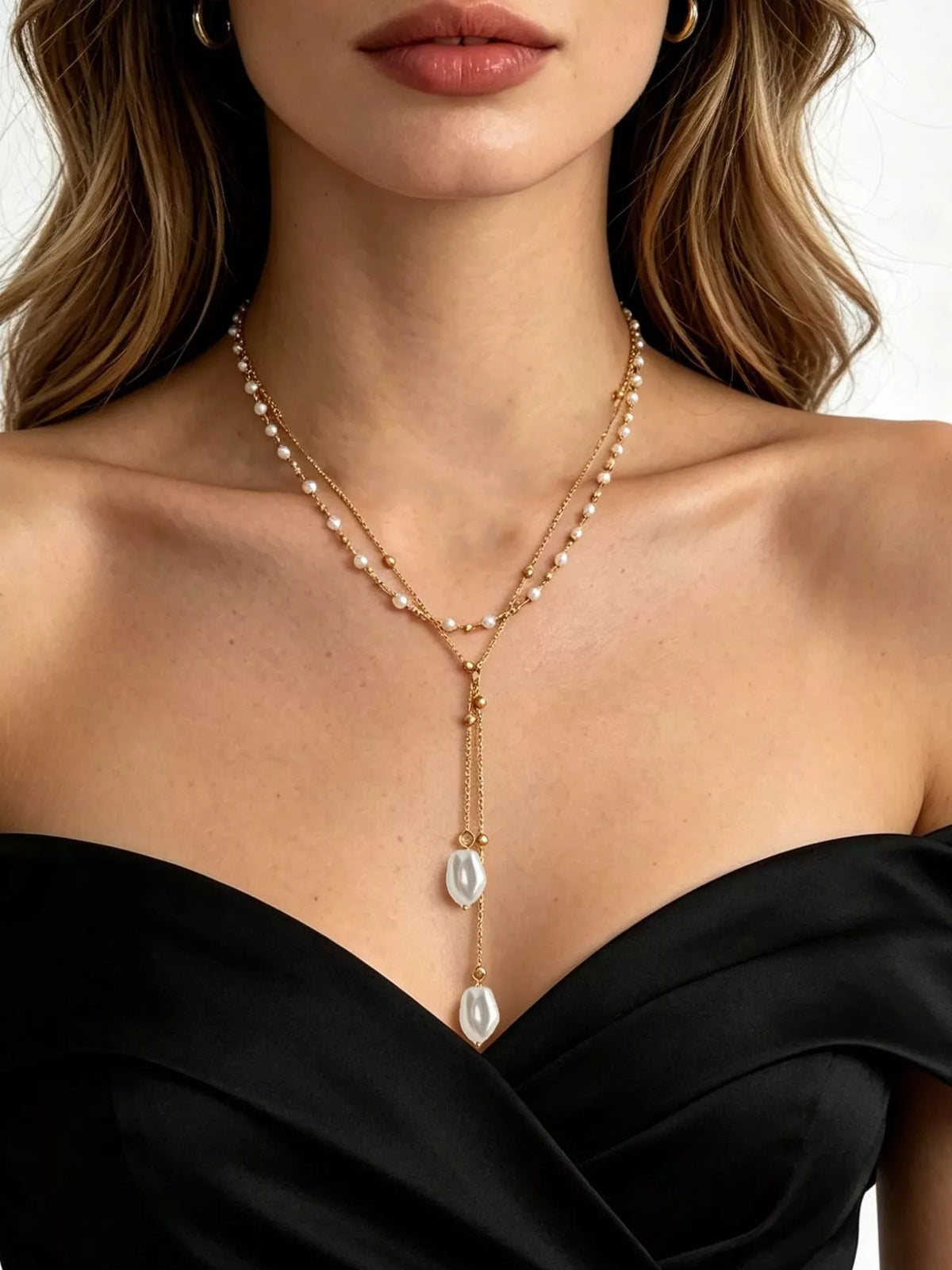 Gold-tone double-layer pearl necklace with long pendant drops worn with a black top