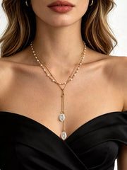 Gold-tone double-layer pearl necklace with long pendant drops worn with a black top
